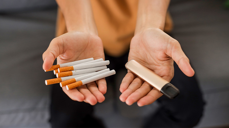 Sigarette e sigaretta elettronica in mano